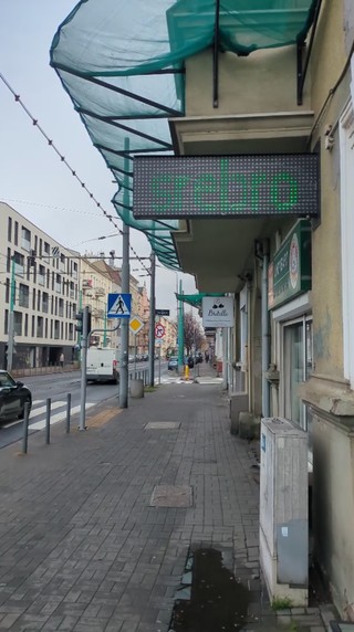Zdjęcie ulicy w Poznaniu. Na ścianie lombardu jest zamontowany zielony ekran LED wystający na chodnik, widać na nim napis „SREBRO”